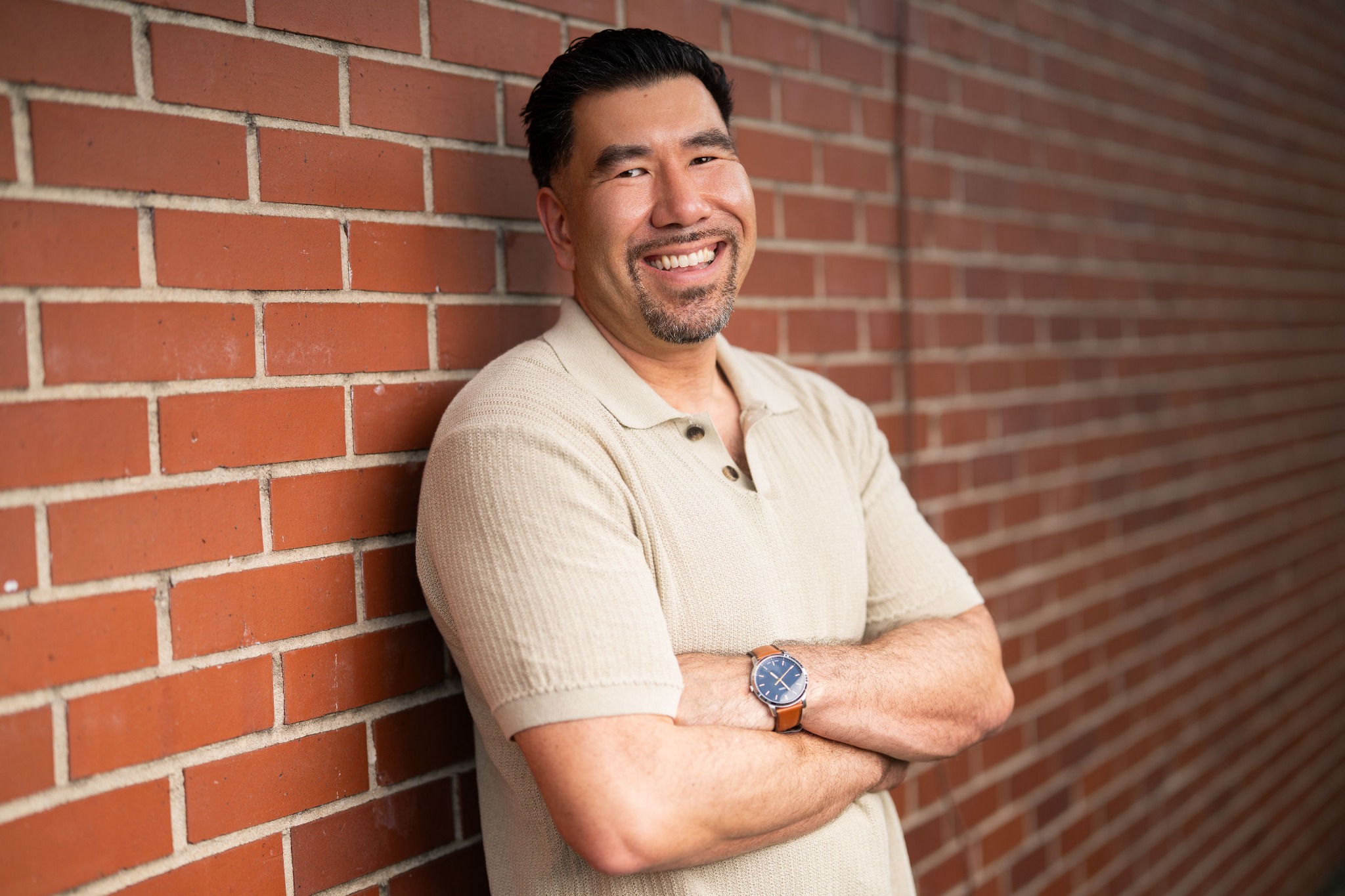 Joshua T. Hartnett smiling beside a brick wall
